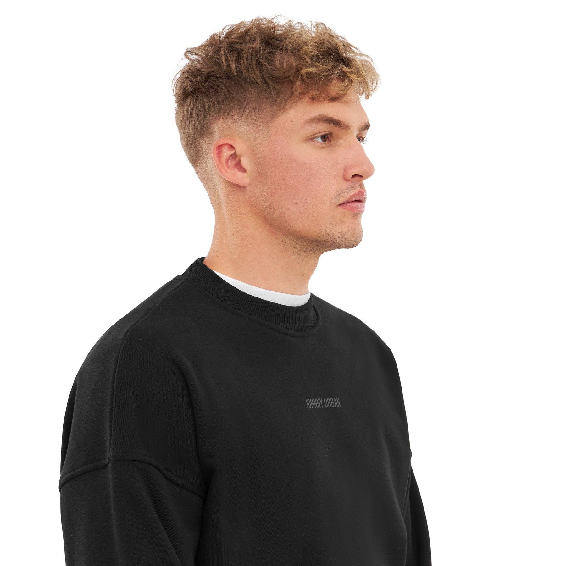 Mann trägt schwarzen Oversized Crewneck 'Carter' Sweatshirt mit kleinem 'Johnny Urban' Print vorne
