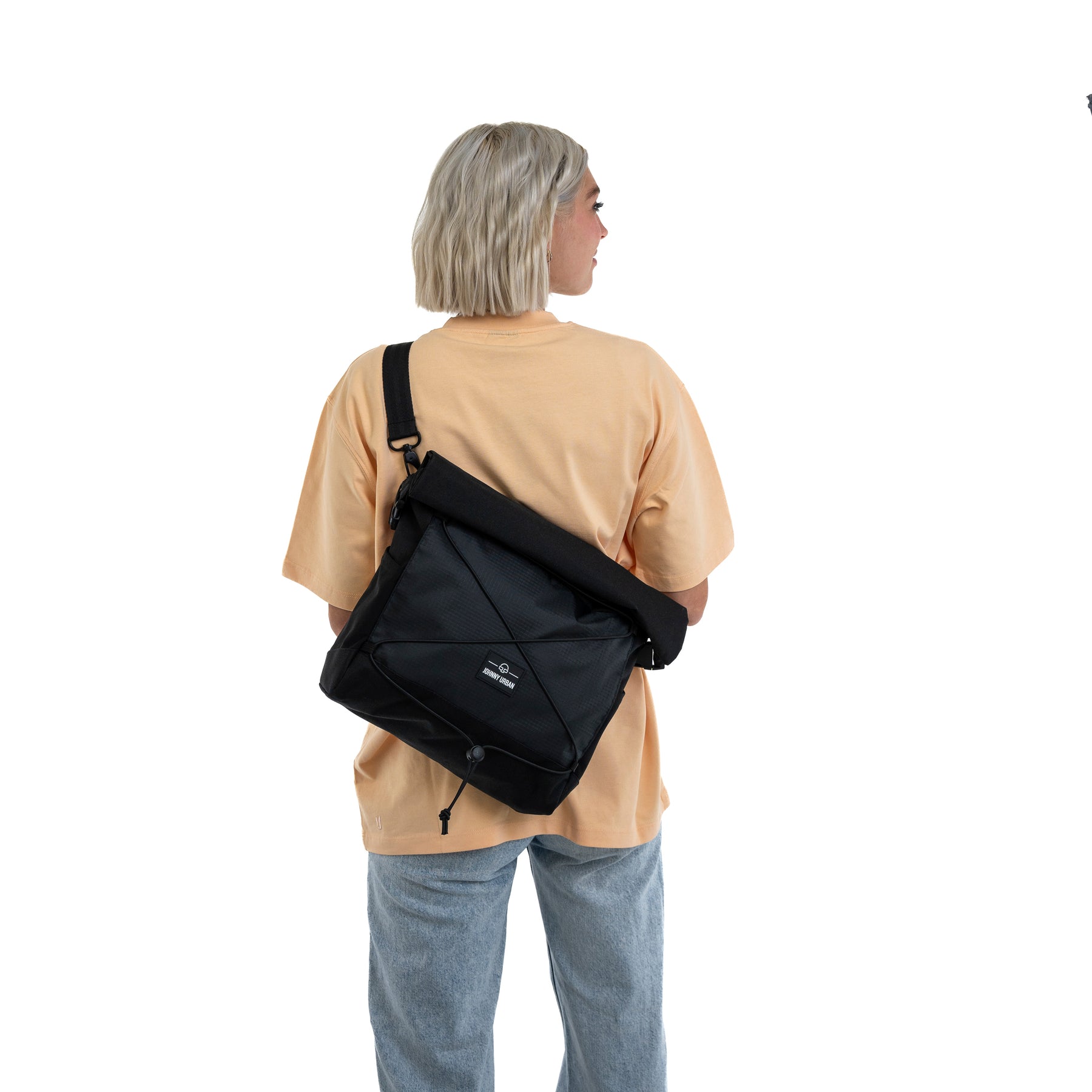 Frau mit schwarzer Umhängetasche 'Dylan' von Johnny Urban, trägt beige Shirt und blaue Jeans, Rückansicht