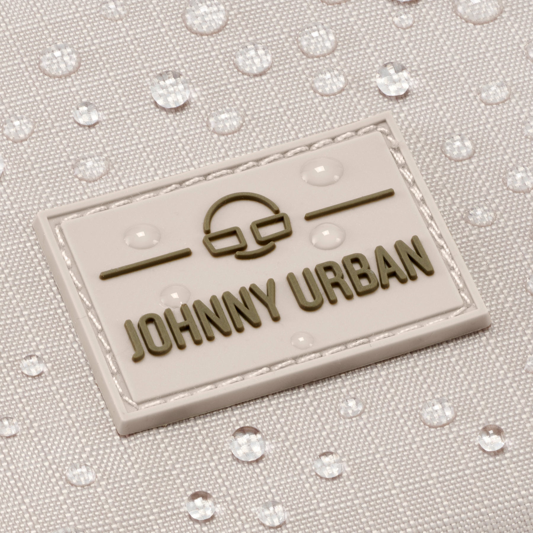 Nahaufnahme des wasserabweisenden beigefarbenen Stoffs mit 'Johnny Urban' Logo auf Umhängetasche Jayden