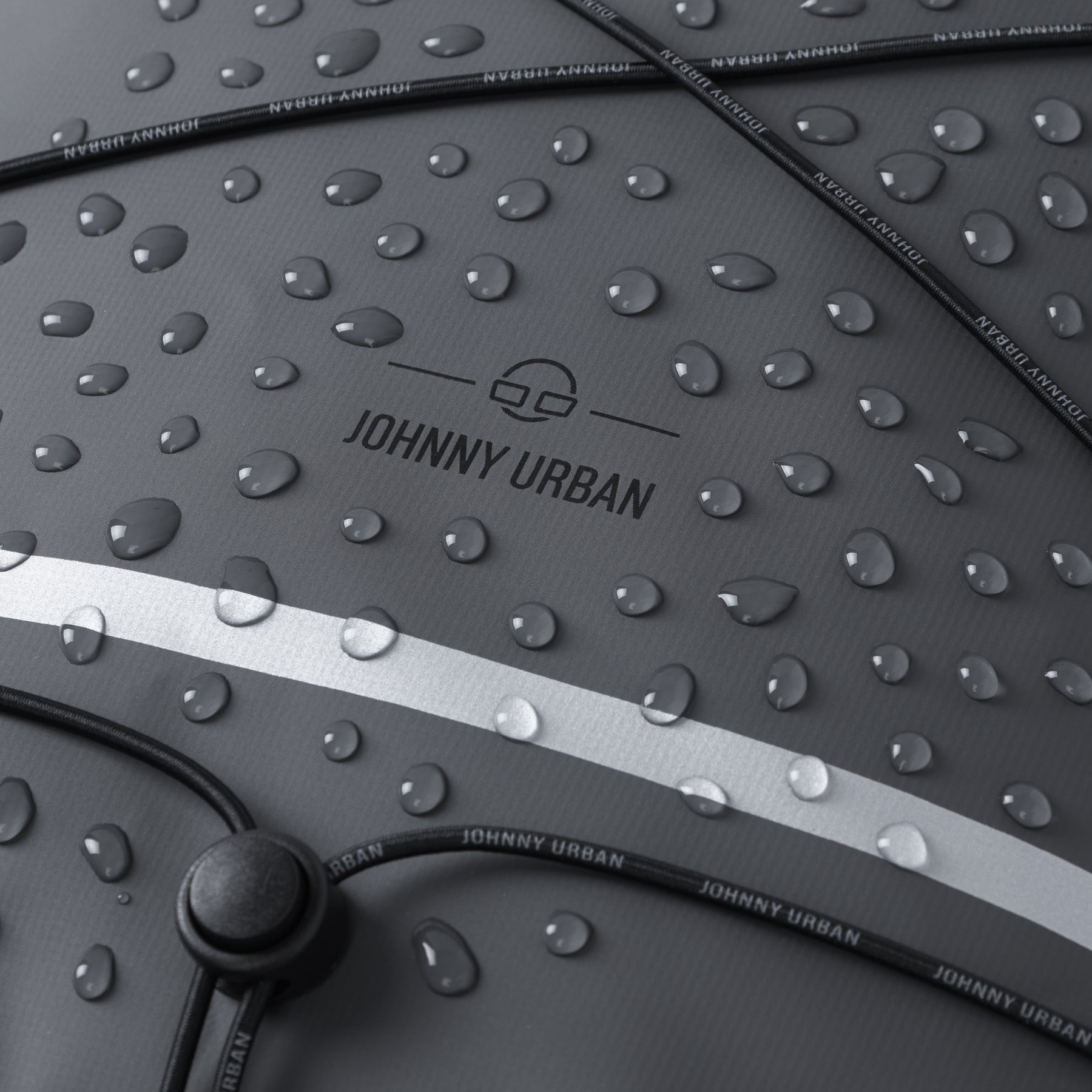 Nahe Nahaufnahme eines wasserdichten Rolltop Fahrradrucksacks 'Myles' von Johnny Urban mit Wassertropfen und reflektierendem Streifen