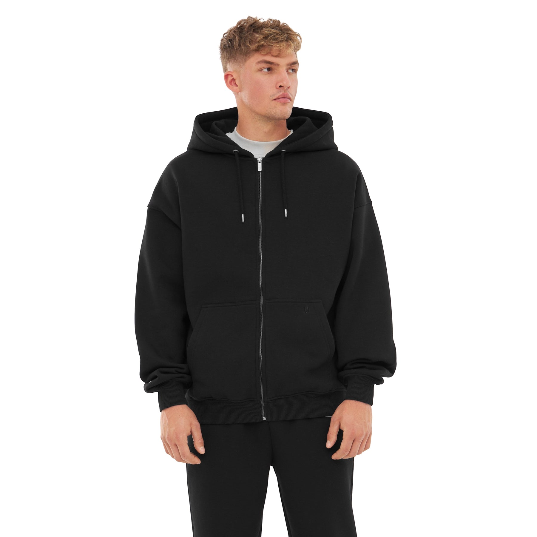 Mann trägt Oversized Zip Hoodie "Caleb" in Schwarz mit Kapuze und Kängurutaschen