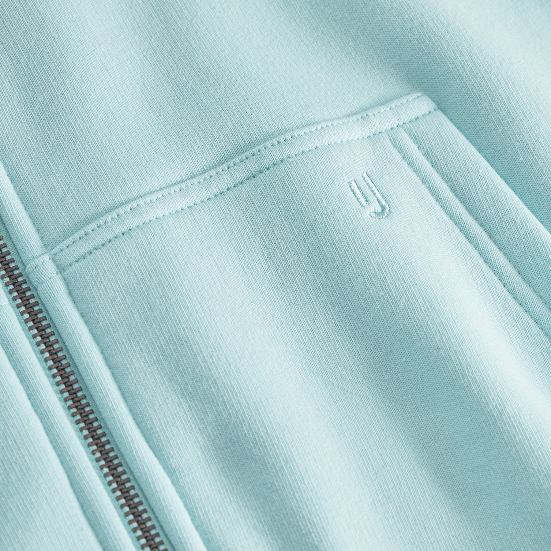 Nahaufnahme der Tasche und des feinen Reißverschlusses des oversized Zip-Hoodies 'Caleb' in eisblau