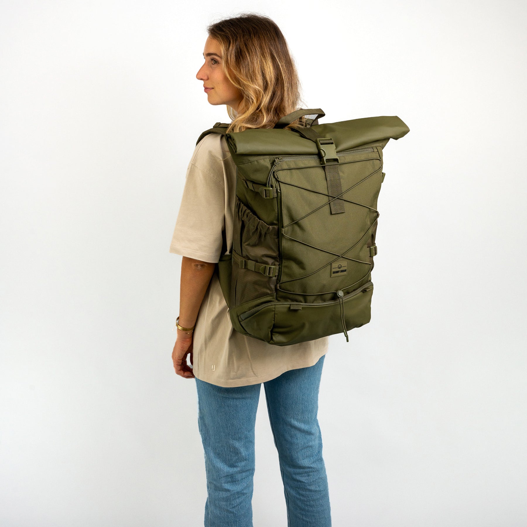 Frau trägt olivgrünen Johnny Urban Reiserucksack 'Allen Large Travel' mit Rollverschluss und elastischem Frontband