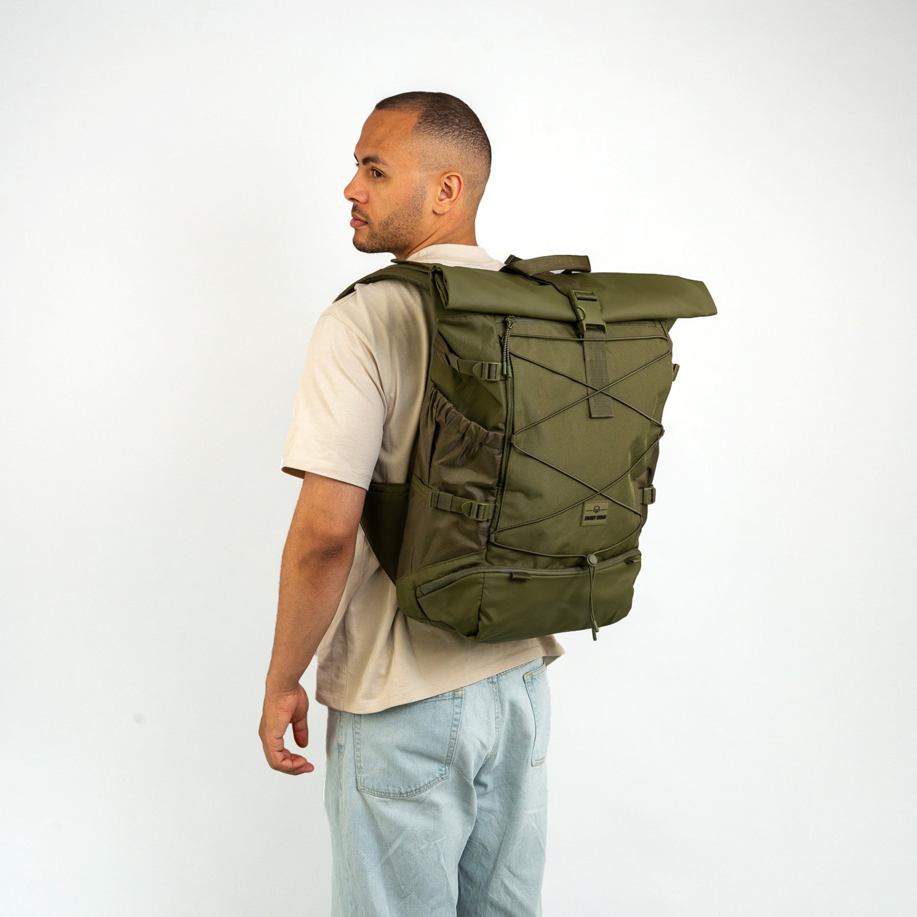 Mann trägt olivgrünen Johnny Urban Reiserucksack 'Allen Large Travel' mit gerolltem Verschluss und elastischem Frontband