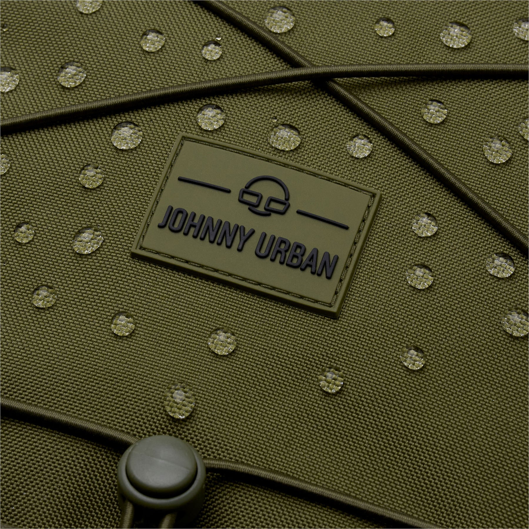 Nahaufnahme des wasserabweisenden Materials des olivgrünen Johnny Urban Reiserucksacks 'Allen Large Travel' mit Wassertropfen darauf