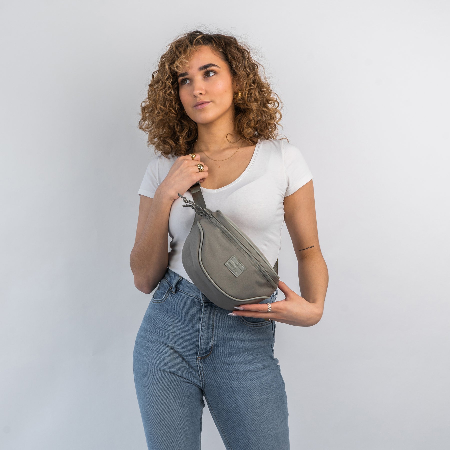 Frau trägt graue nachhaltige Bauchtasche 'Ben' über weißem T-Shirt und blauen Jeans