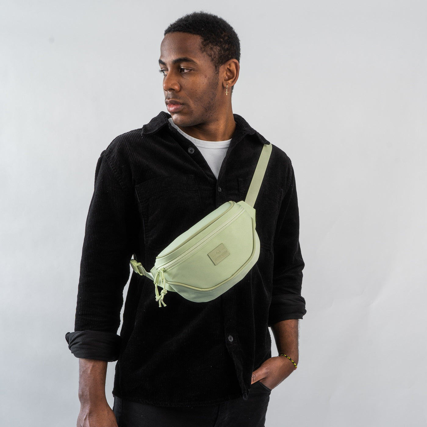 Mann trägt limegrüne Bauchtasche 'Ben' quer über der Brust, schwarze Jacke und weißes T-Shirt