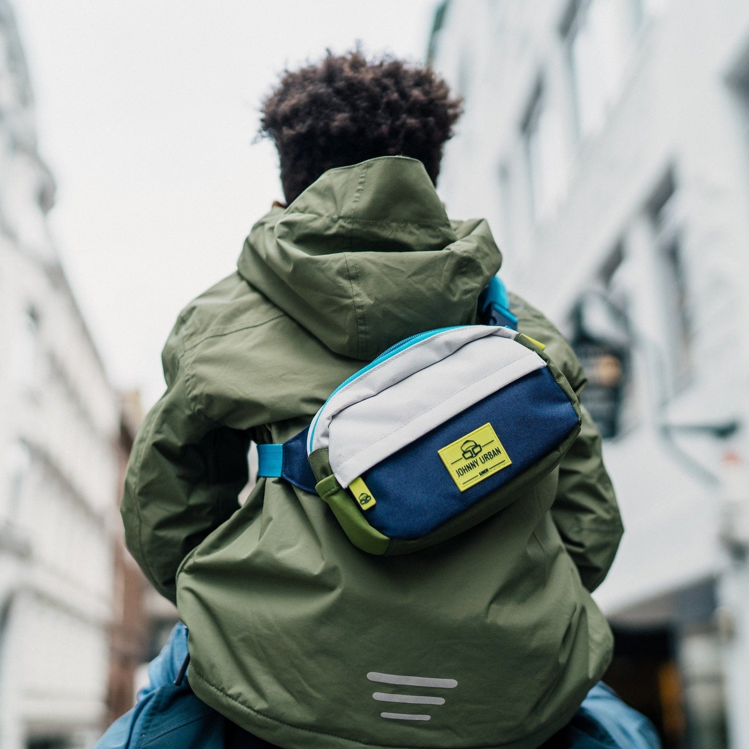 Kind trägt grüne Jacke und bunte Kinder Bauchtasche 'Felix' von Johnny Urban auf dem Rücken