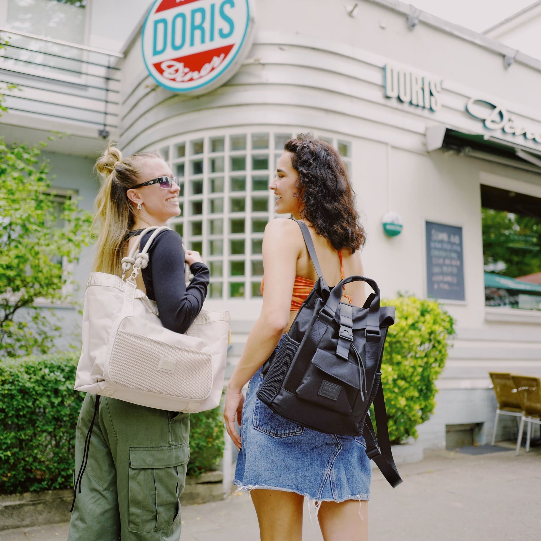 Zwei Frauen vor einem Café, eine trägt den schwarzen Damenrucksack 'Jules' von Johnny Urban