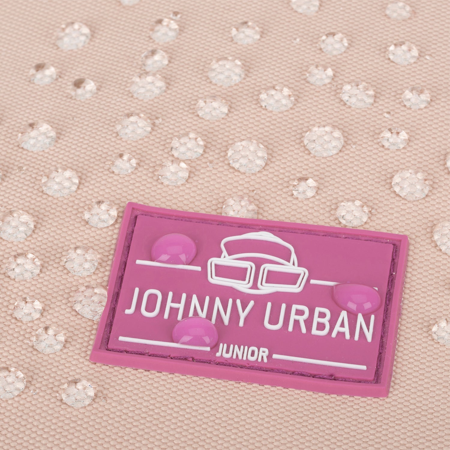 Nahaufnahme des wasserabweisenden Stoffs mit pinkfarbenem Johnny Urban Junior Logo auf dem Kinderrucksack 'Liam'