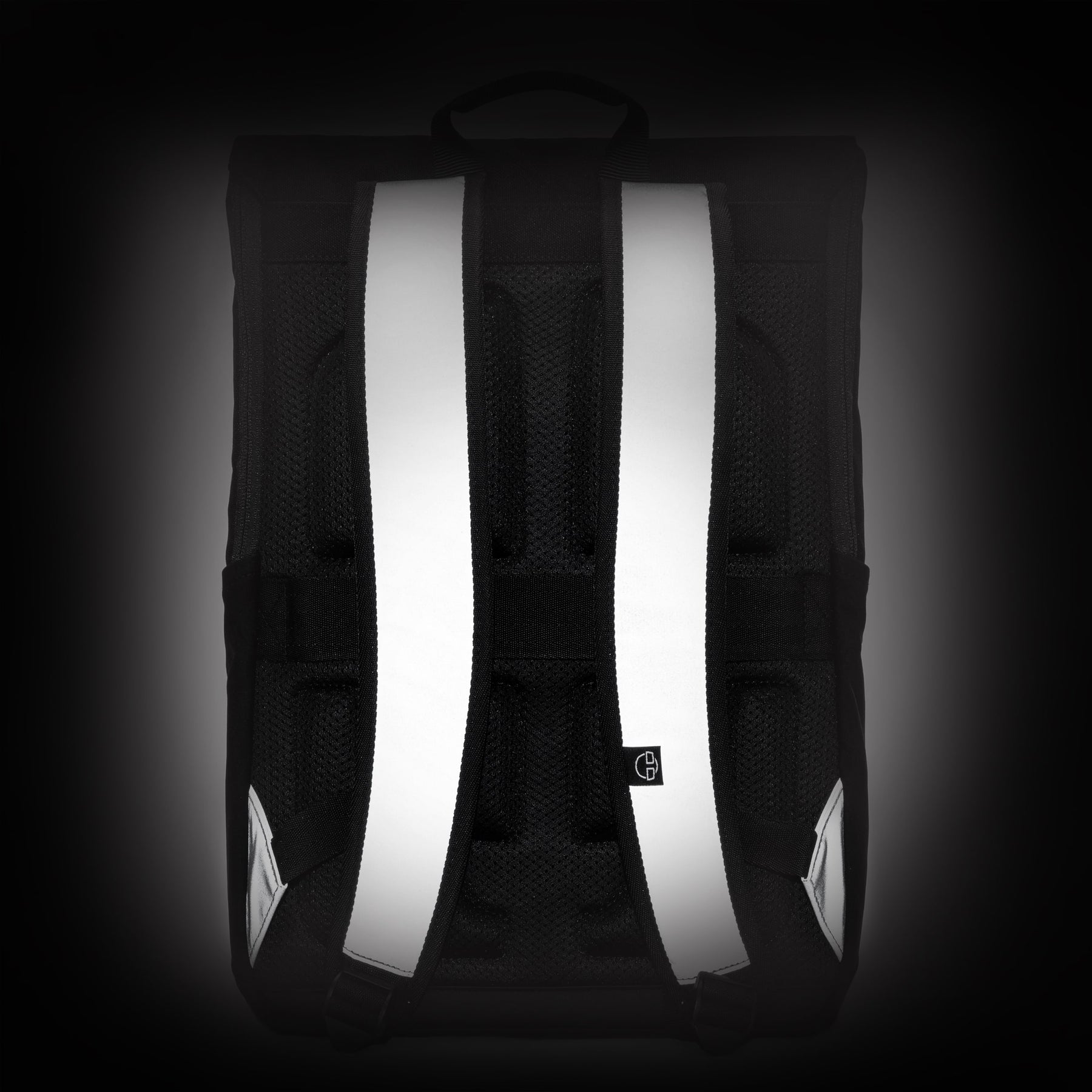Reflektierende Schulterriemen des schwarzen und grauen Rucksacks 'Mika' von Johnny Urban vor dunklem Hintergrund