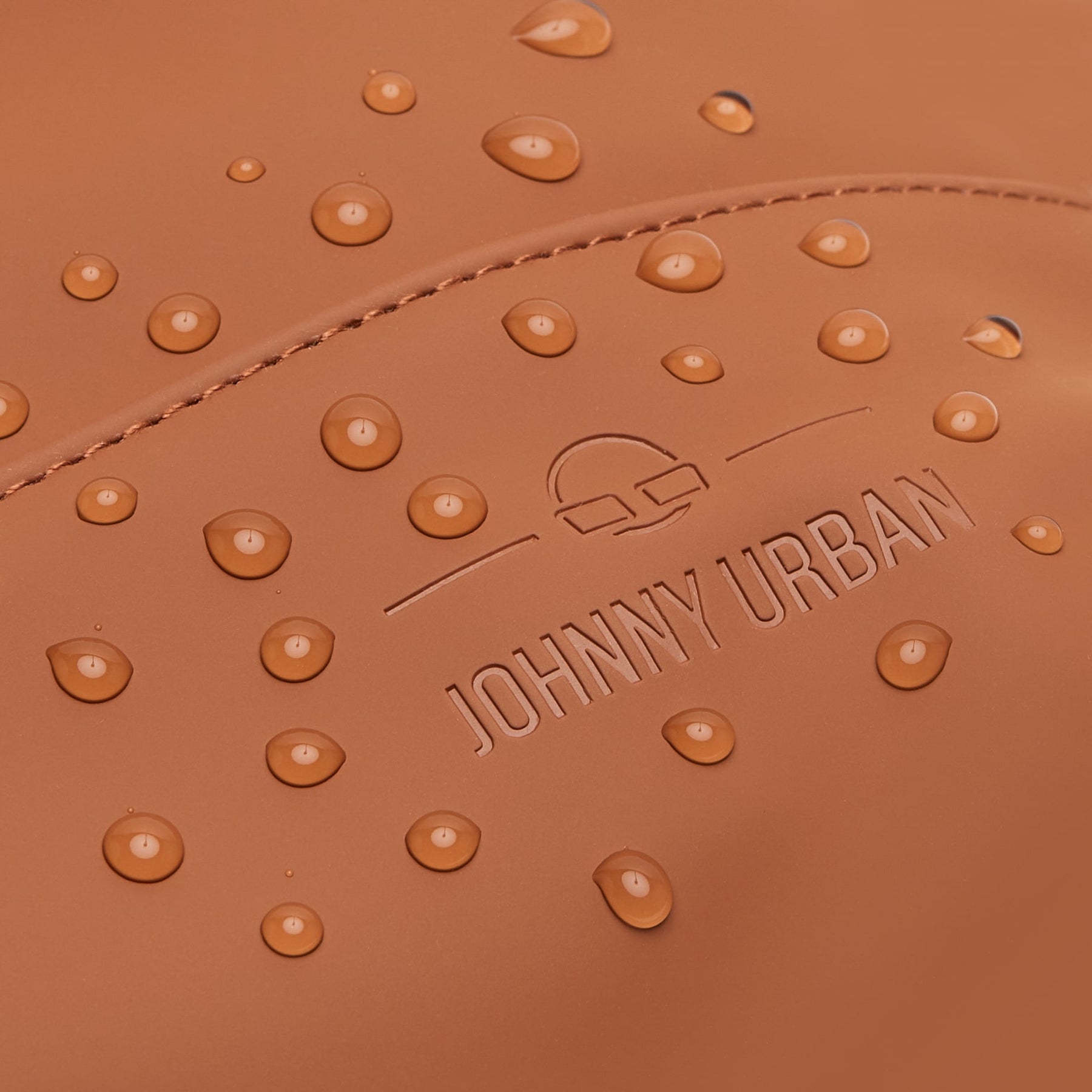 Nahaufnahme des caramelfarbenen Damenrucksacks 'Ruby' von Johnny Urban mit sichtbaren Wassertropfen auf wasserdichtem Material