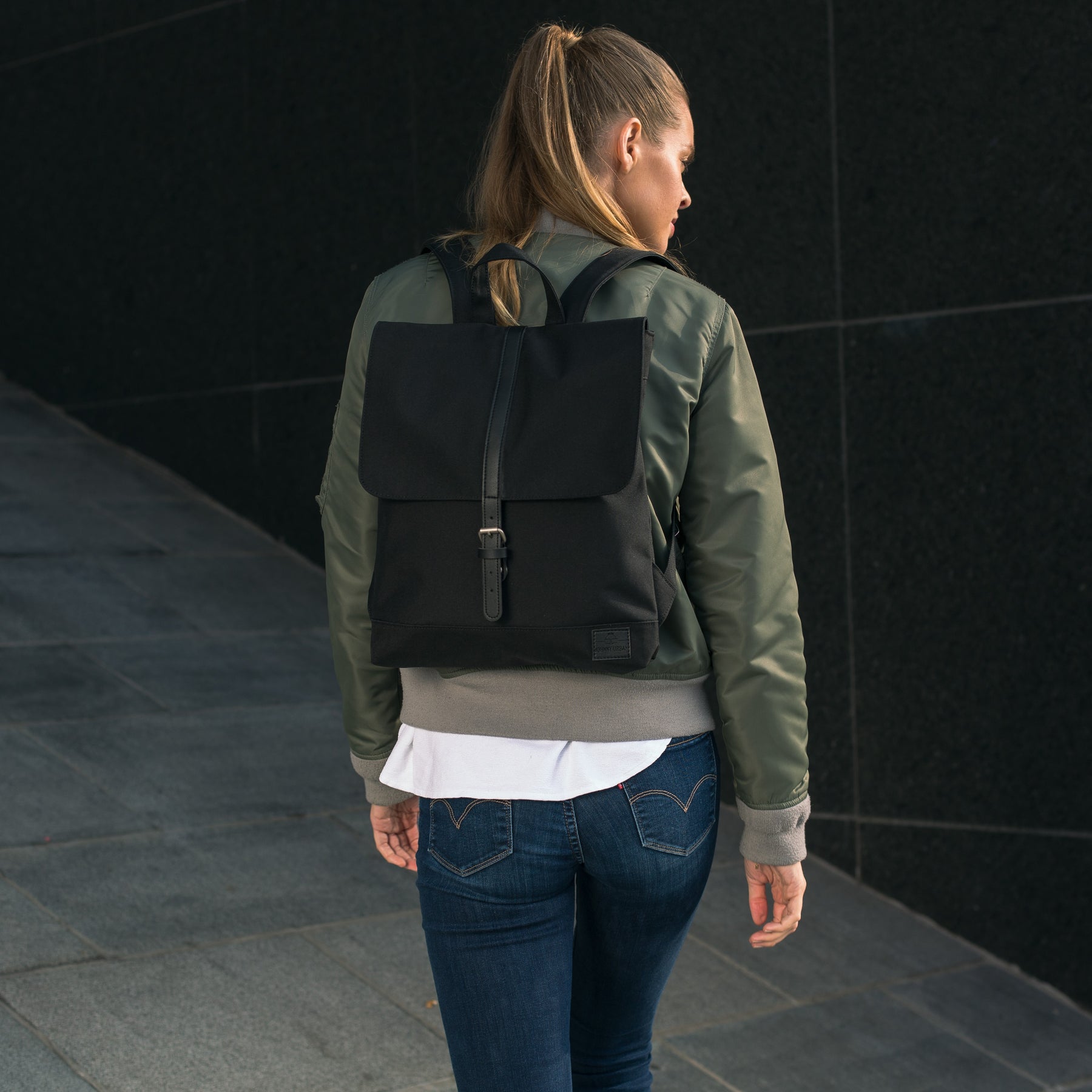 Frau trägt schwarzen Rucksack 'Mia' von Johnny Urban, umgeben von urbaner Kulisse