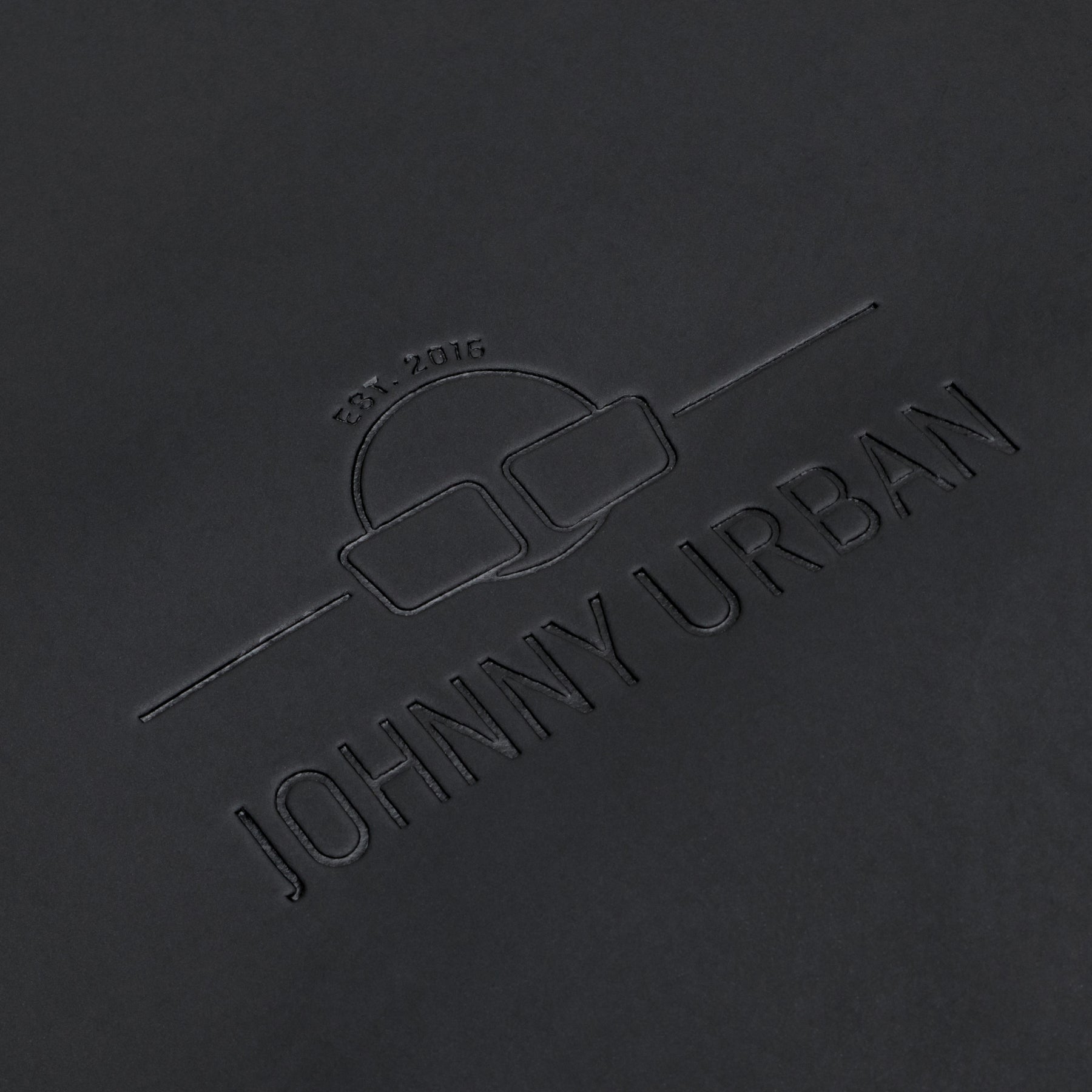 Prägung des Johnny Urban Logos auf dem schwarzen Rolltop Rucksack 'Henry'
