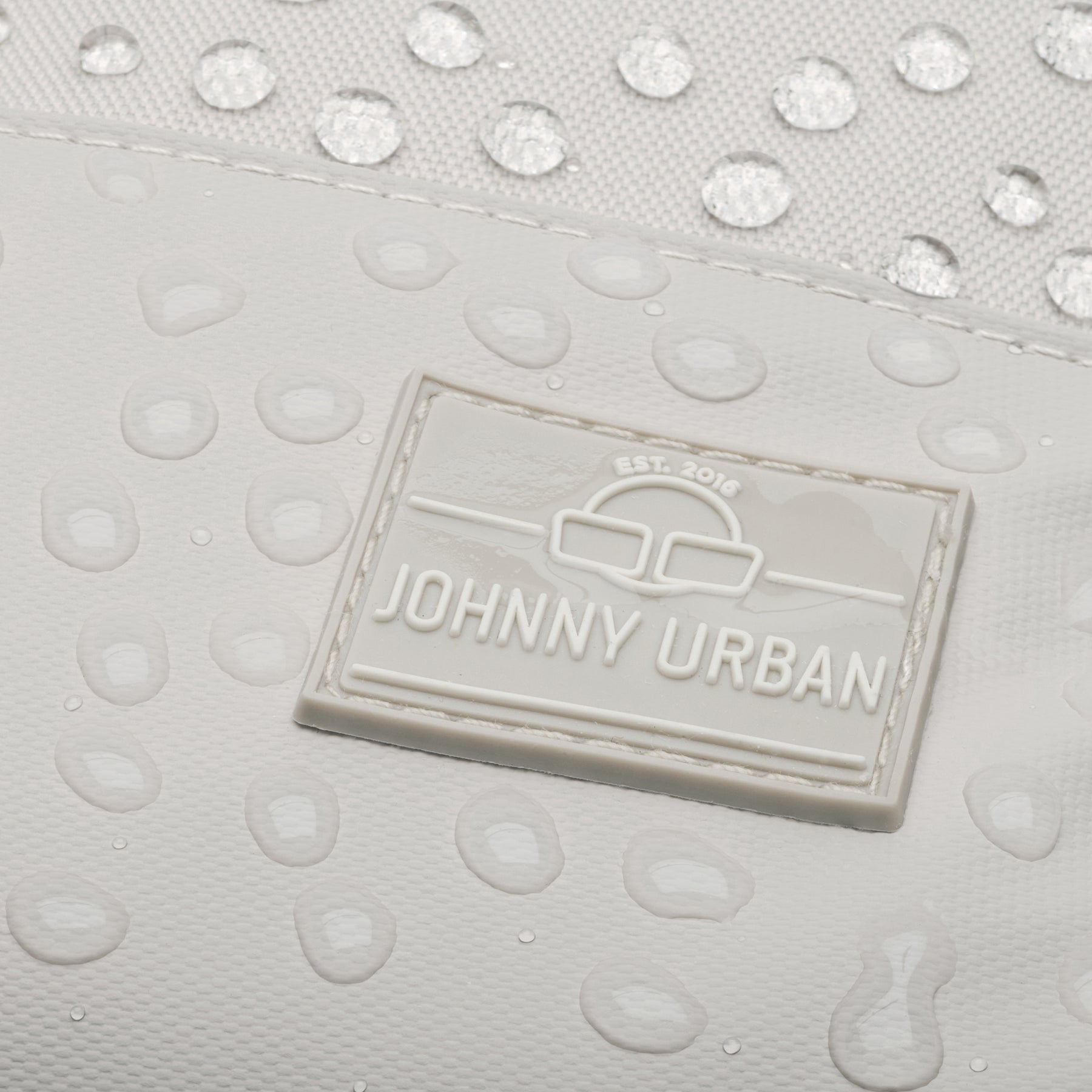 Nahe Ansicht des beigen, wasserdichten Rucksacks 'Mika' mit Johnny Urban Logo und Wassertropfen
