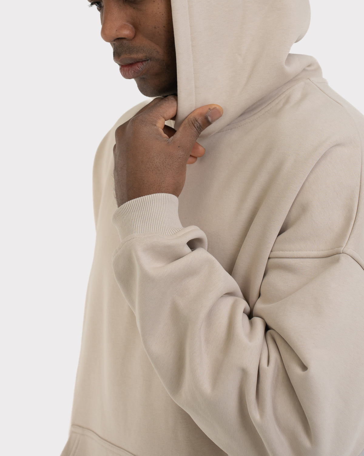 Mann mit kurzem blondem Haar trägt einen oversized Hoodie 'Cody' in hellem Beige mit Kapuze