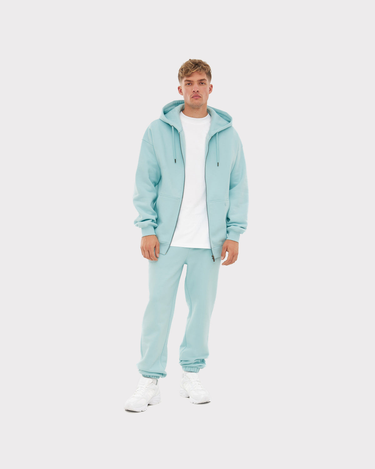 Mann trägt Jogginghose 'Owen' in ice-blau mit passendem Kapuzenpullover und weißem T-Shirt