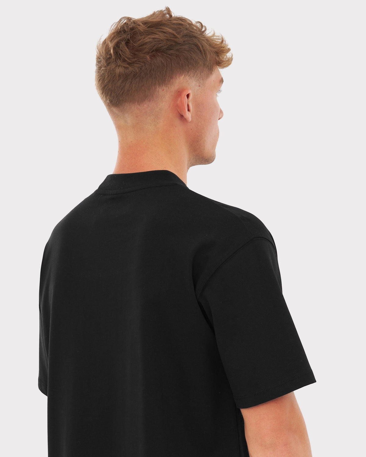 Rückansicht eines Mannes mit kurzen blonden Haaren, trägt schwarzes oversized T-Shirt 'Sammy'