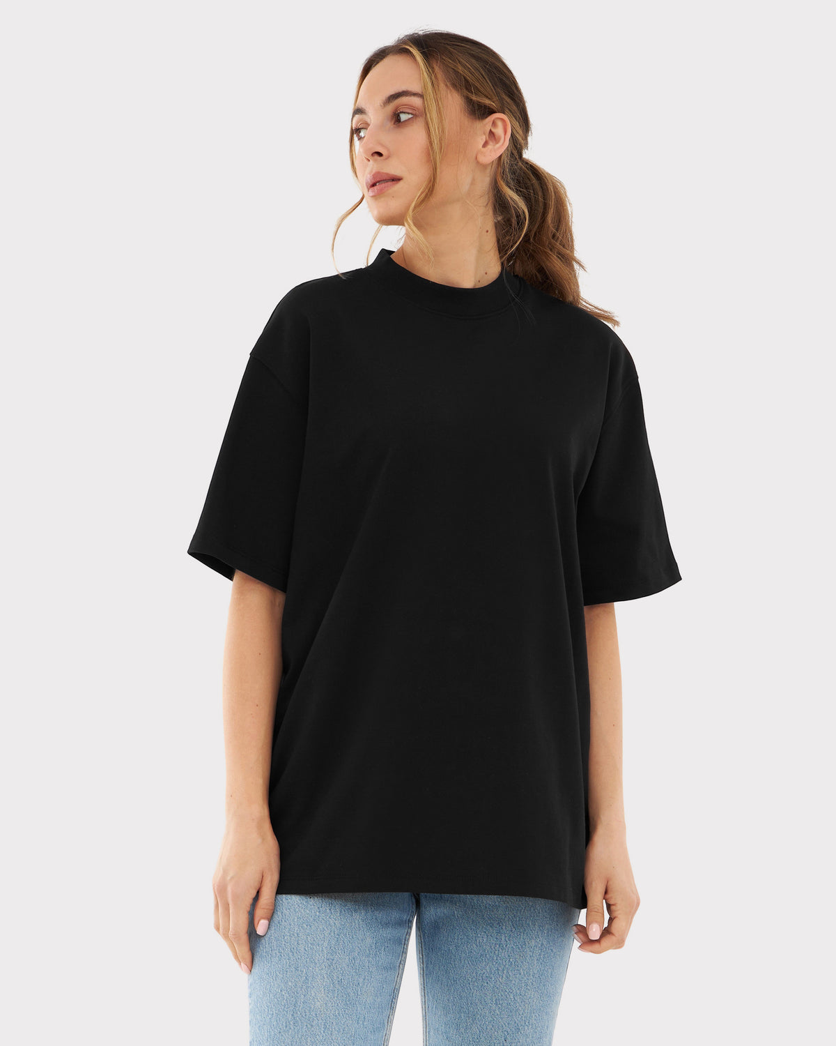 Frau trägt schwarzes Oversize-T-Shirt ohne Aufdruck und blaue Jeans