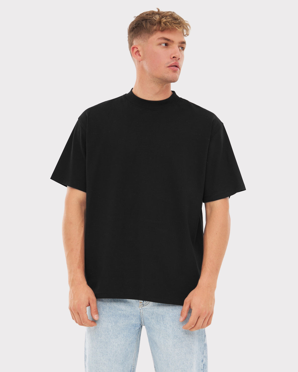 Mann trägt schwarzes Oversize-T-Shirt ohne sichtbaren Print und helle Jeans