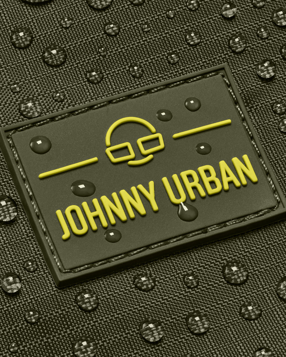 Nahaufnahme des wasserabweisenden olivgrünen Johnny Urban Rolltop Rucksacks Allen Large Move mit gelbem Logo und Wassertropfen