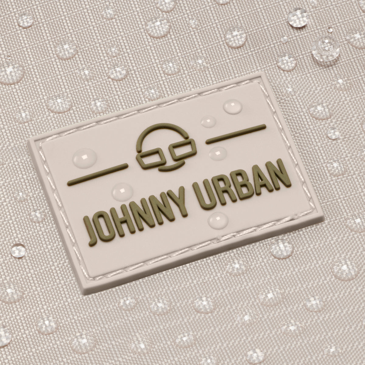 Nahe Aufnahme des wasserabweisenden sandfarbenen Johnny Urban Rolltop-Rucksacks 'Allen Large Move' mit Markenlogo und Wassertröpfchen
