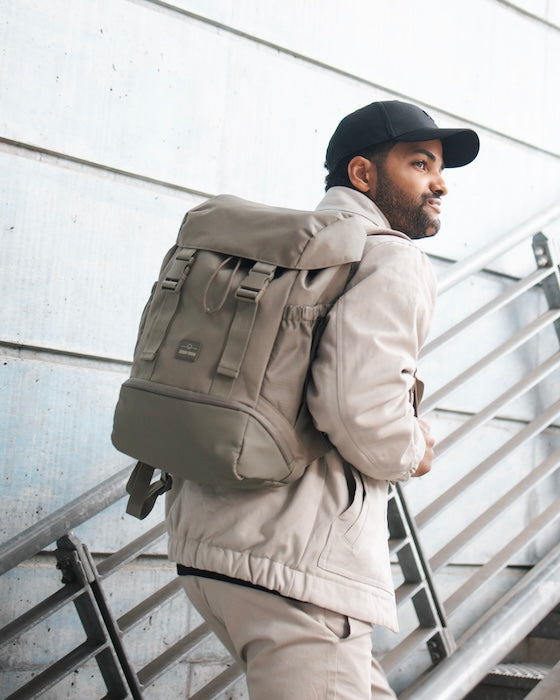 Mann mit Cap läuft mit Rucksack auf dem Rücken eine Treppe hoch.