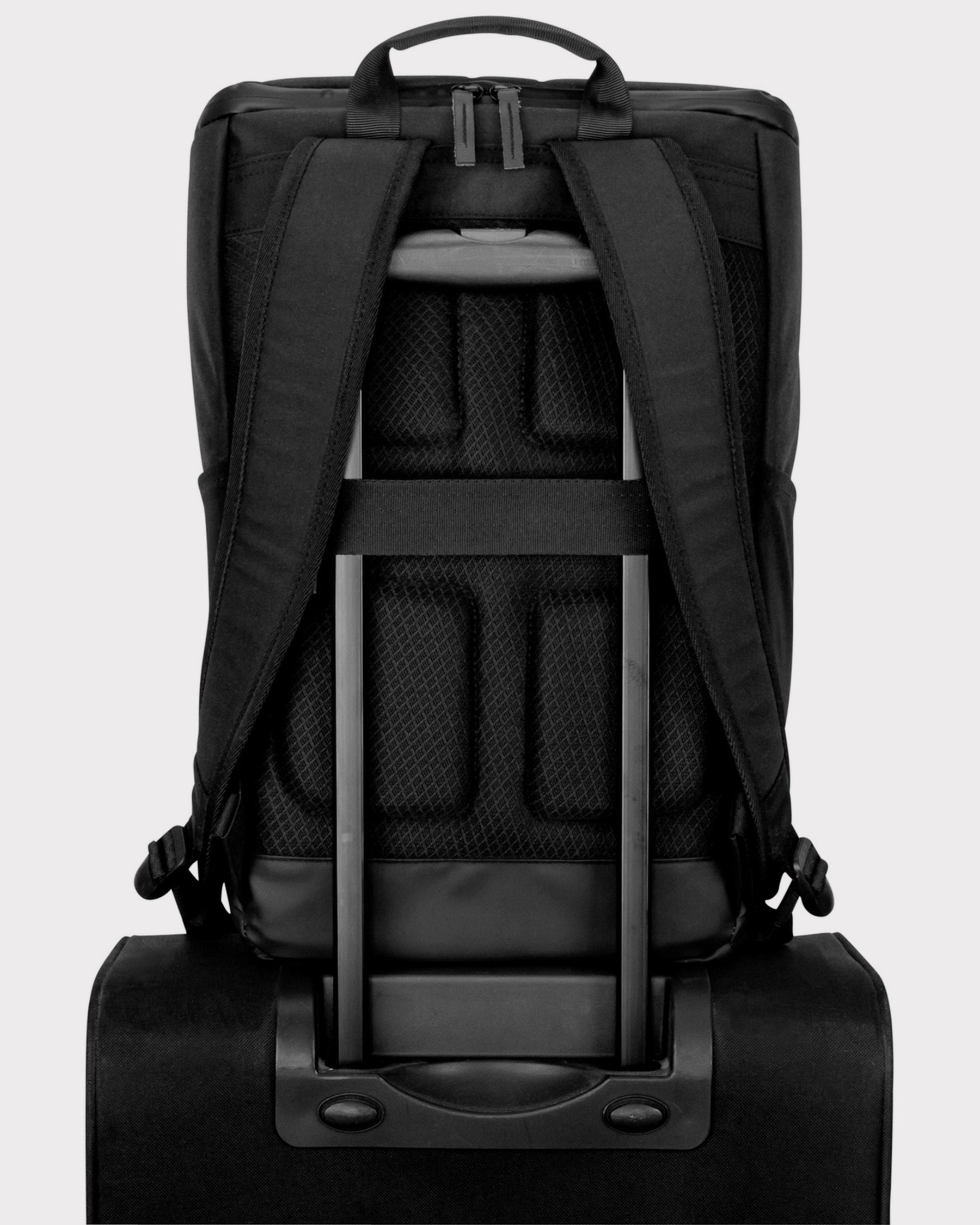 Geschlossener schwarzer Business-Rucksack 'Jasper' mit gepolsterten Trägern auf einem Trolley-Griff befestigt