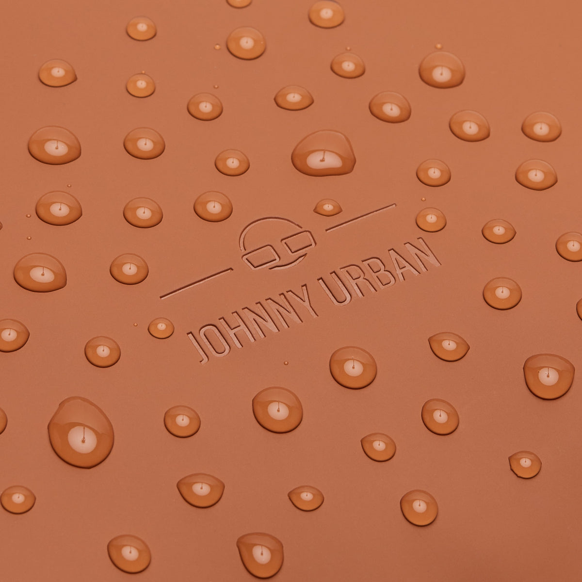Nahaufnahme von wasserabweisendem Material mit eingeprägtem 'Johnny Urban' Logo und Wassertröpfchen