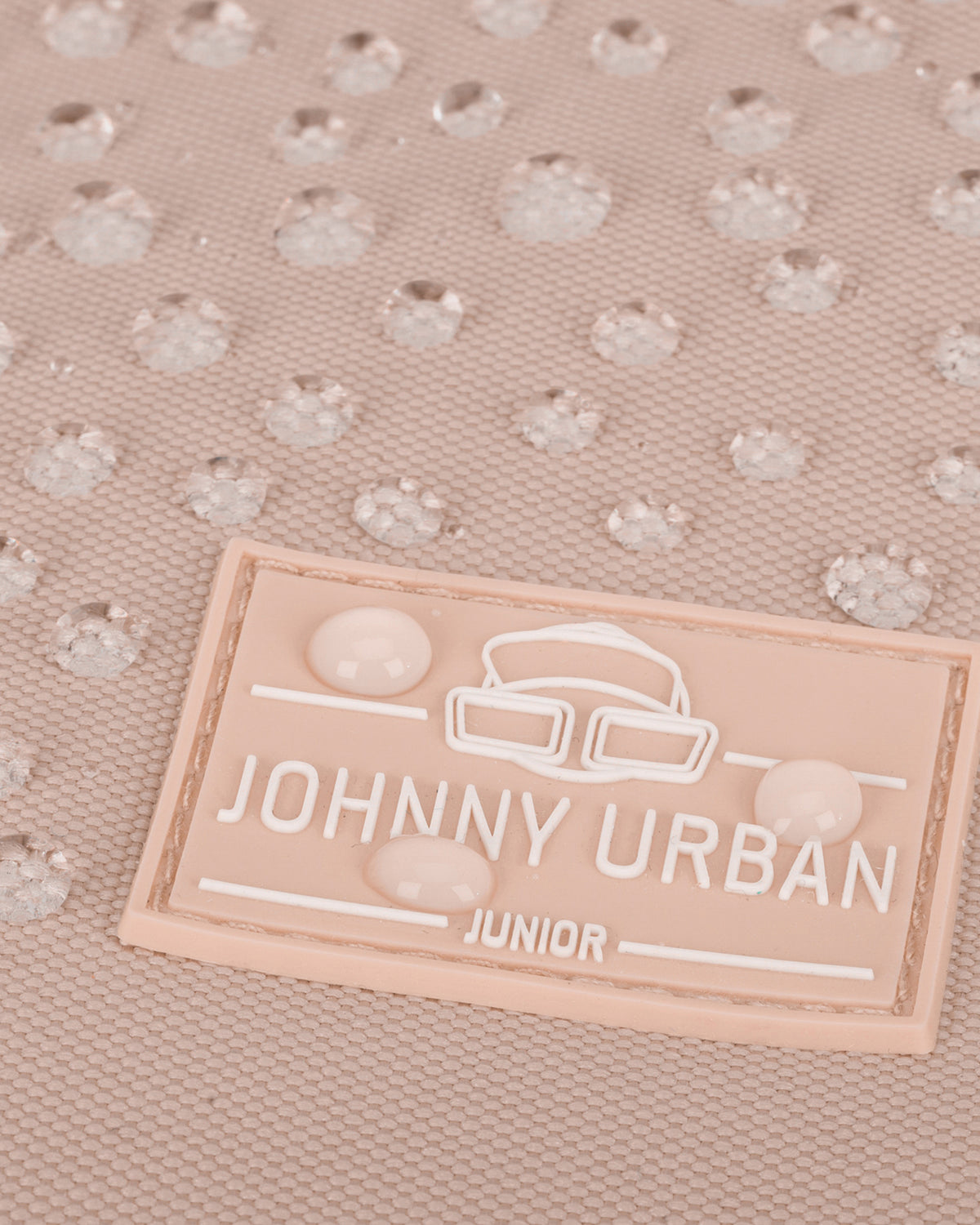 Nahaufnahme des rosa Johnny Urban Junior Labels mit Wassertröpfchen auf wasserdichtem Material