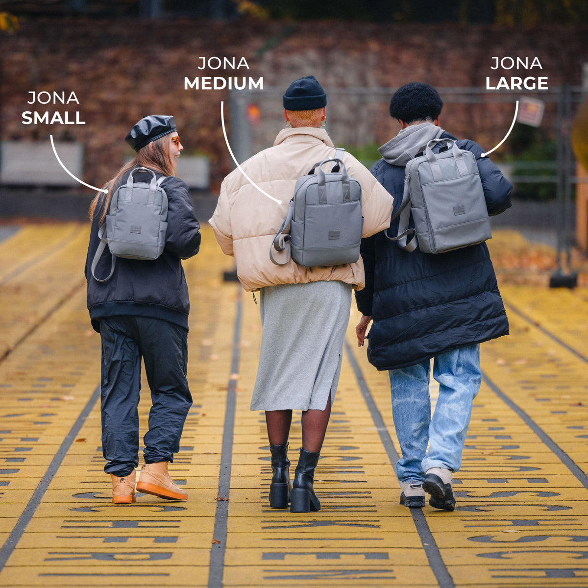 Drei Personen von hinten mit grauen Johnny Urban Jona Rucksäcken in den Größen Small, Medium und Large
