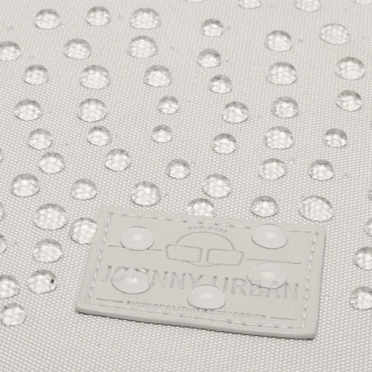 Beige wasserabweisendes Material mit Regentropfen und Johnny Urban Logo auf Tasche