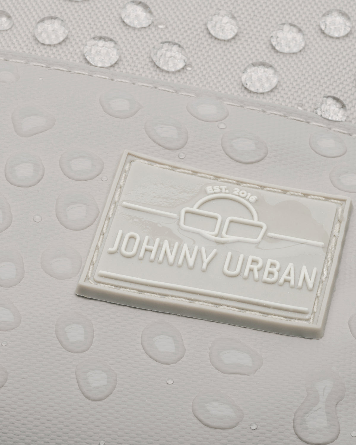 Nahe Ansicht des beigen, wasserdichten Rucksacks 'Mika' mit Johnny Urban Logo und Wassertropfen
