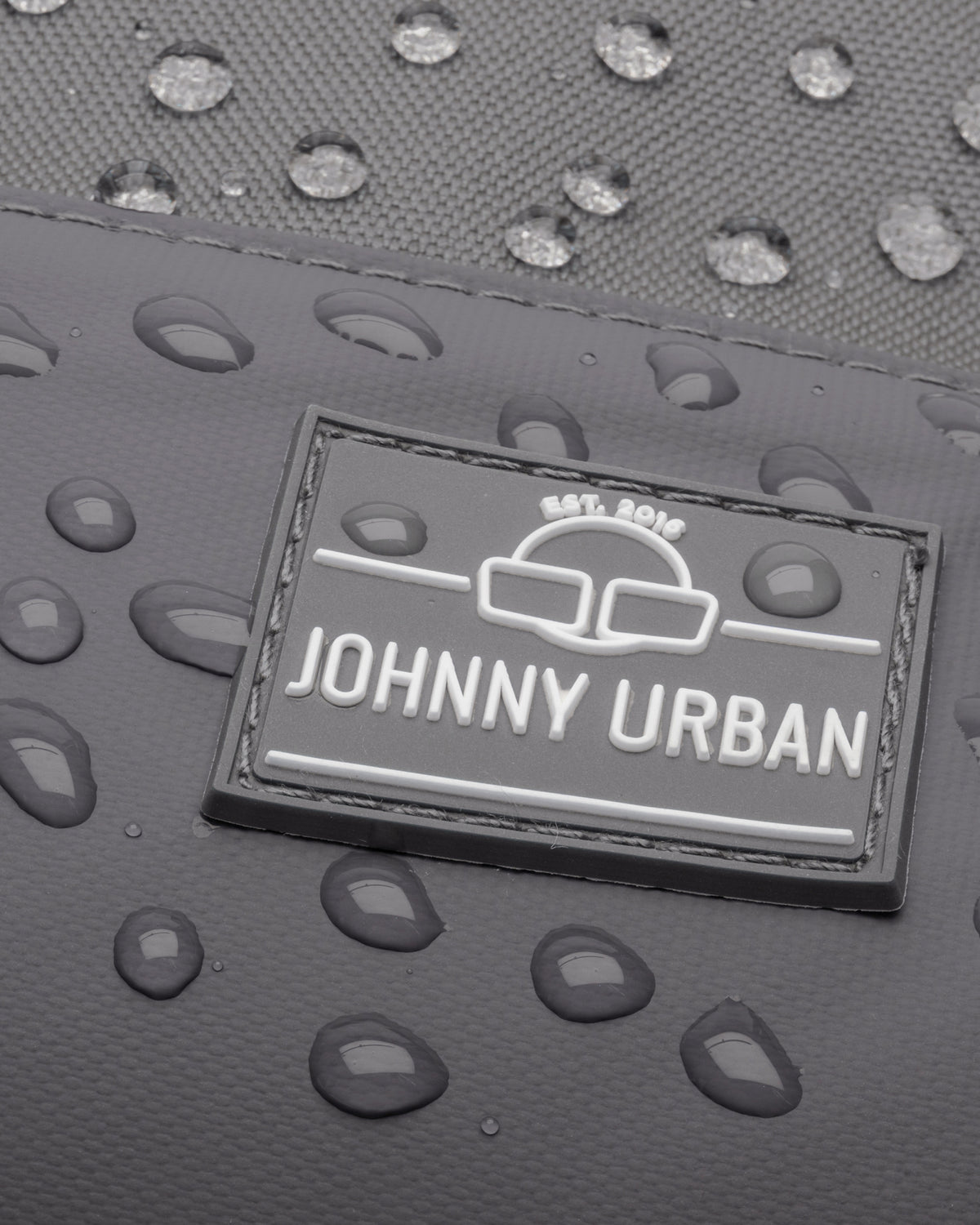 Nahaufnahme des wasserdichten dunkelgrauen Johnny Urban Rucksacks 'Mika' mit Wassertropfen auf der Oberfläche